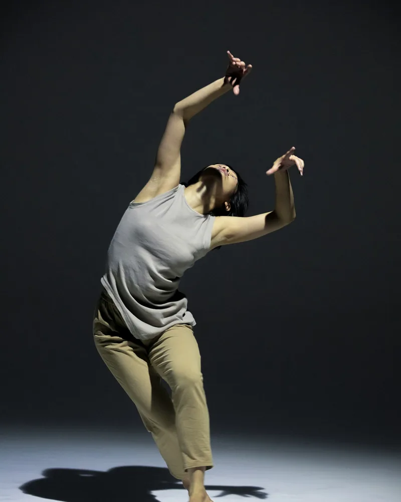 Bailarín en una postura de danza contemporánea, con el torso inclinado y los brazos extendidos